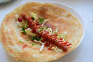 将卷心菜丝、香菜段、香肠放在饼中间，挤上番茄酱