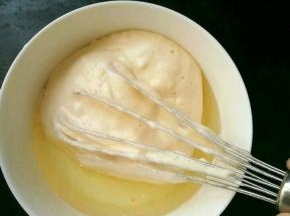 取适量蛋糕糊，放到牛奶和玉米油的混合物里，翻拌均匀。