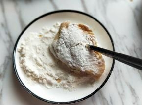 首先将腌制好的鸡翅放入面粉器具中，裹满干面粉。