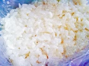 保鲜盒铺好保鲜膜放入一层糯米
