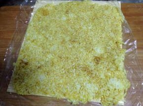 把拌好的米饭倒入，用铲子铺平并压紧