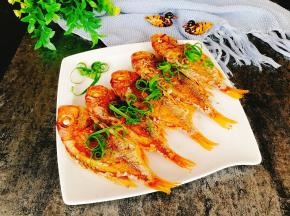 将椒盐均匀撒鱼上，葱用手撕摆上装饰