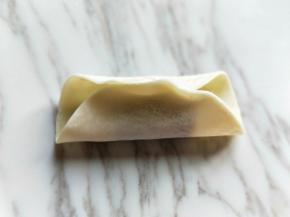 将饺子皮对折，如图。