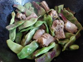 这时倒入油豆角，中火翻炒均匀后，盖上锅盖，焖一会儿。