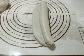 称重分割成三等份，擀成长舌状从一边卷至另一边收口朝下放入模具中。