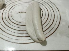 称重分割成三等份，擀成长舌状从一边卷至另一边收口朝下放入模具中。