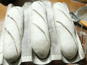 发酵好的面包取出，表面过筛上一层薄薄的面粉，用刀片快速划出割口。