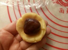取20克的面团按扁放入一个豆沙馅包好，收口捏紧。
