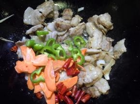 放入胡萝卜片和尖椒、干红辣椒翻炒几下