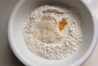 面粉中间挖洞，依次倒入牛奶酵母液、鸡蛋、盐、10克白糖和20克牛奶