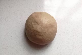 发酵好的面团取出挤压排气，盖保鲜膜再静置15分钟