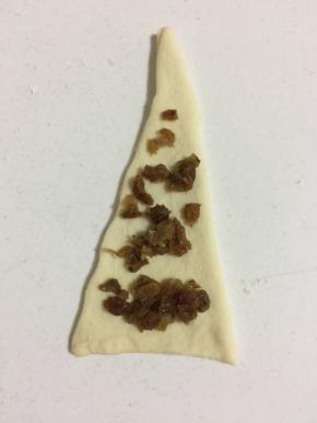 取一个面片，均匀的铺上切碎的葡萄干。