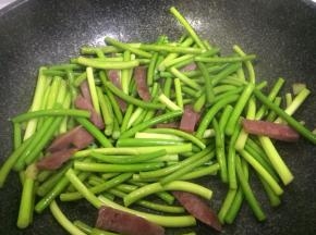 加适量盐，改中火慢慢翻炒，让蒜苔释放一定水分