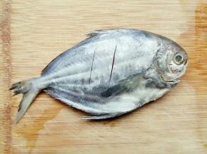 洗干净的鱼放占板拿刀划两刀