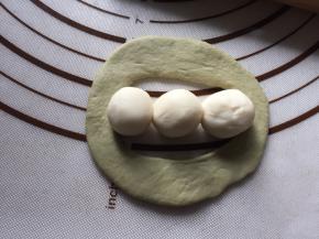 再将面皮展开，在中心缺口上，放三颗白色小球