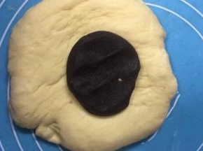 醒发好的面团用手压扁在放上压扁的红豆沙