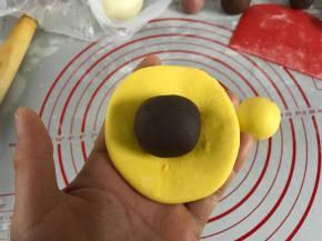 取一个剂子按成圆面片包入豆沙馅。