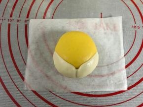 把包入豆沙馅的面团稍整成上面小下面大的形状后把白色面片贴在黄色面团的下半部。