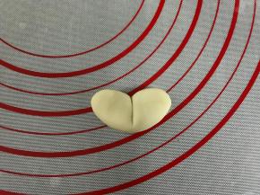 取10克左右的白色面团搓成椭圆形。用刮板在中间压出痕后按扁。