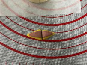 把粉色放在黄色面团上压平后中间切开。