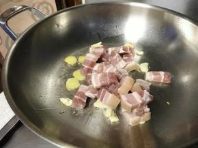 下入五花肉块煸炒。