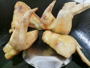 煎好的鸡翅用锅勺顶在边上掉油