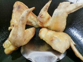 煎好的鸡翅用锅勺顶在边上掉油
