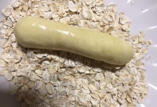 在面包胚表面沾水放在燕麦片盘里滚一圈