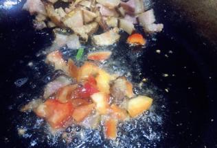 把腊肉推在锅的一遍，放入甜椒