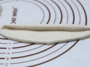 将面团分割成55克大小，揉至长舌状从一边卷起。