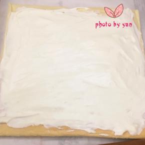 带花纹的那面盖上油纸，翻面，切去尾端，抹上淡奶油。也摆上喜欢的水果，把剩下的淡奶油盖在水果上；