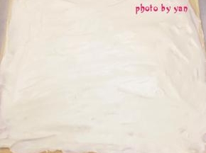 带花纹的那面盖上油纸，翻面，切去尾端，抹上淡奶油。也摆上喜欢的水果，把剩下的淡奶油盖在水果上；