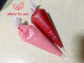 取2个小碗，各盛出一点面糊，分别滴入适量红丝绒液，调成红色和粉色面糊，装入裱花袋；