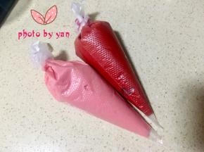 取2个小碗，各盛出一点面糊，分别滴入适量红丝绒液，调成红色和粉色面糊，装入裱花袋；