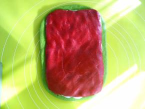 取一半甜菜根香芋馅，用同样的方法擀成长方形，裁掉保鲜袋，将甜菜根香芋馅铺在麻薯上，用手按压一下，将三份材料压实