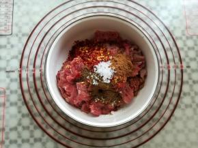 准备一个大碗，在牛肉上放入孜然粉，五香粉，辣椒和盐简单混合