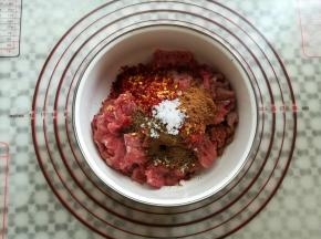 准备一个大碗，在牛肉上放入孜然粉，五香粉，辣椒和盐简单混合