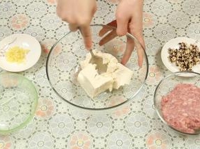 将豆腐放入一个大碗里，用勺子背面压成豆腐泥，肉末跟豆腐的比例为1:1。