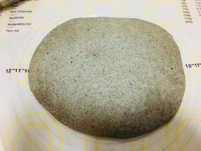 松弛过后，将面团按扁。拍掉气泡