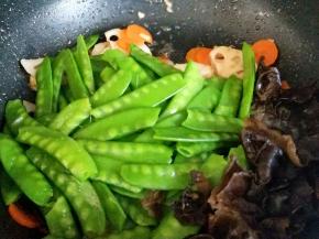 加入焯水的荷兰豆和黑木耳，翻炒均匀。