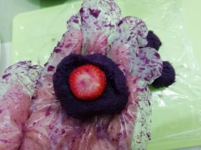 在把紫薯按扁把草莓尖部放在底部，然后将草莓包好