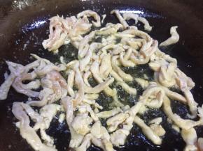 七成热时倒入鸡肉丝快速翻炒至变白