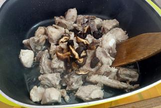 再把焯好水的排骨煸至微黄，加入香菇。