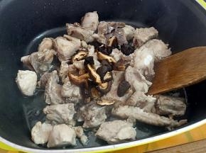 再把焯好水的排骨煸至微黄，加入香菇。