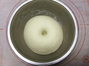 把面团取出放入不锈钢盆中，（直接放在面包桶里启动发酵功能也可以），不锈钢盆盖上保鲜膜，进行第一次发酵。发至两倍大，用手指沾一下面粉在面团中间戳一个洞，不回缩不塌陷就发酵好了。