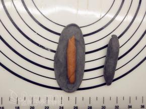 竹炭小剂子一样擀成椭圆形，中间放上可可面团，将它包起来。