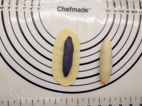 取出一个原味面团，一样将它擀成椭圆形，中间放上竹炭面团，将它包起来。这里就需要全面包住啦。