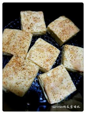5、看见豆腐块两面金黄，撒上精盐、孜然粉和辣椒粉。