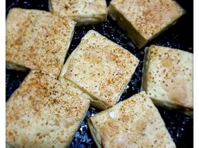 5、看见豆腐块两面金黄，撒上精盐、孜然粉和辣椒粉。