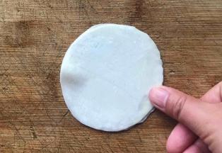 盖上另一张饺子皮，用手指轻轻按压或捏紧边缘处，一定要捏紧
